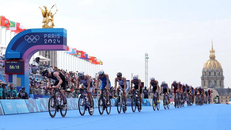 Samuel Dickinson, da Grã-Bretanha, em ação com atletas à frente dos Invalides durante o Triathlon