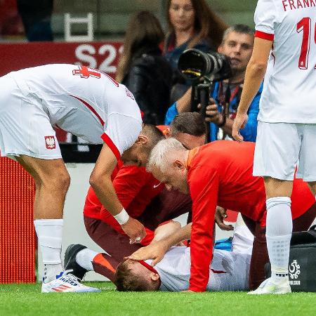 Karol Swiderski, da seleção da Polônia, é atendido no gramado após se machucar comemorando gol contra a Turquia