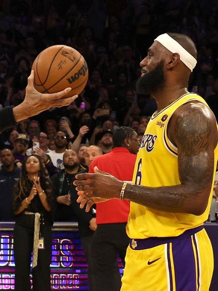 Kareem Abdul-Jabbar entrega bola de basquete a LeBron James, simbolizando a quebra do recorde de mais pontos na história da NBA. - Harry How/Getty Images
