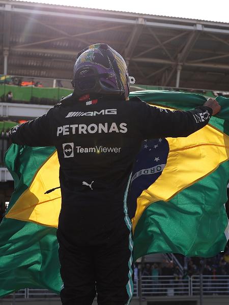 Lewis Hamilton agita a bandeira do Brasil para comemorar com a torcida a vitória do GP de São Paulo. 14/11/2021 - LARS BARON/Pool via REUTERS