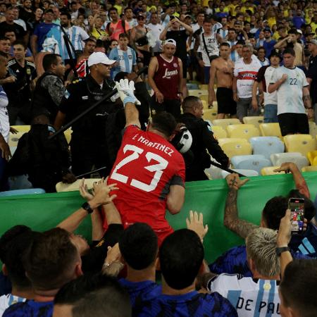 Dibu Martínez, goleiro da Argentina, tenta segurar cassetete de policial durante briga na arquibancada do Maracanã, no jogo contra o Brasil