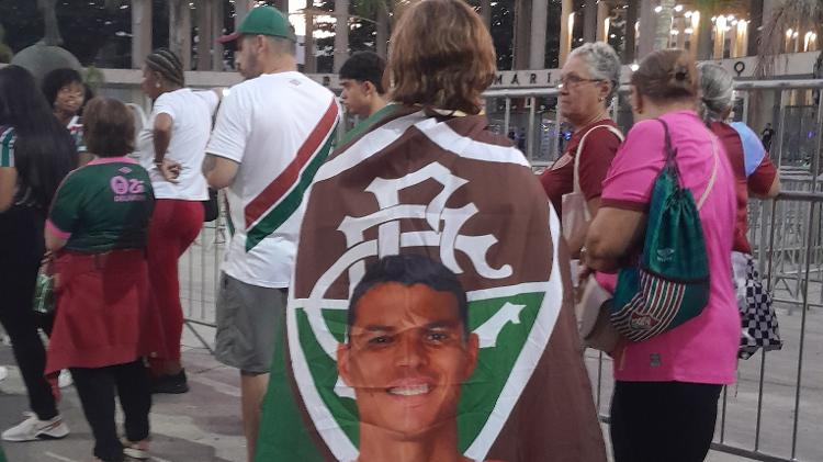 Torcedora do Fluminense enrolada em bandeira com o rosto de Thiago Silva