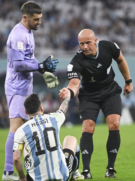 O árbitro polonês Szymon Marciniak auxilia Messi a se erguer durante jogo entre Argentina e Austrália nas oitavas de final da Copa do Mundo no Qatar. 03/12/2022 - Li Ga/Xinhua