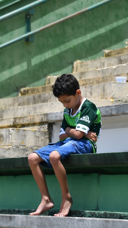 No dia do acidente, Richard Nascimento, de sete anos, foi fotografado cabisbaixo na arquibancada da Arena Condá, estádio da Chapecoense - Nelson Almeida/AFP Photo