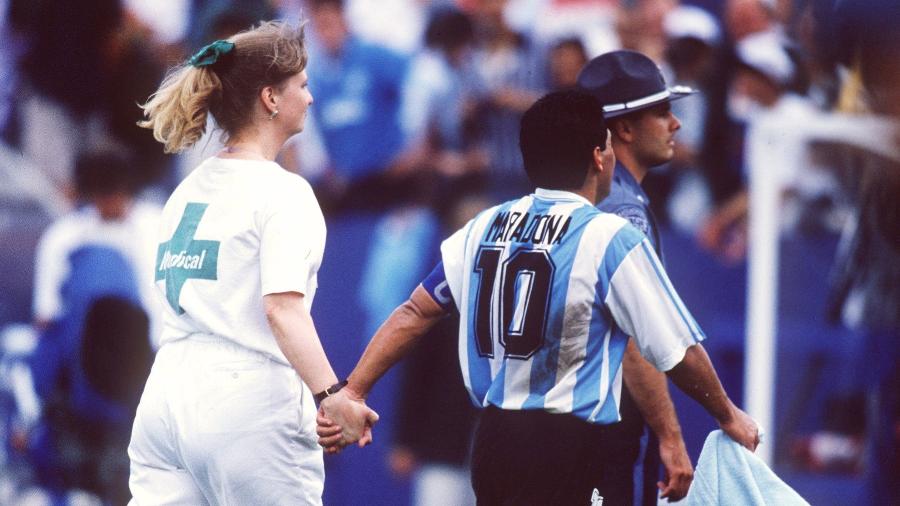 Diego Maradona em campo acompanhando de representante do controle antidoping