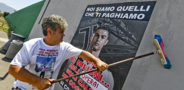 Manifestação do lado de fora da fábrica da FCA em Pomigliano d?Arco, no sul da Itália, organizada por um sindicato e por cinco operários demitidos pela empresa, nesta quarta-feira, 11 de julho. O cartaz mostra uma foto de Cristiano Ronaldo e a frase: "Para Ronaldo, 400 milhões de euros... Aos operários, apenas chutes no saco" - Ciro Fusco/Ansa - Ciro Fusco/Ansa