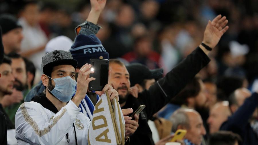Após a Espanha confirmar os primeiros casos de coronavírus nesta semana, torcedores usam máscaras de proteção em partida entre Real Madrid e Manchester City, pela ida das oitavas de final da Liga dos Campeões, em Madri  - Susana Vera/Reuters