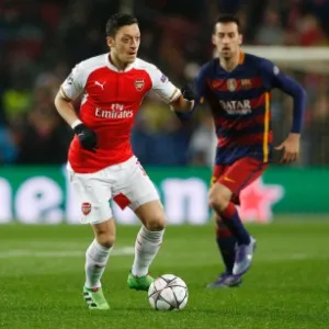 Ozil tenta a jogada acompanhado pela marcação de Busquets na partida entre Barcelona e Arsenal pela Liga dos Campeões - Carl Recine/Reuters