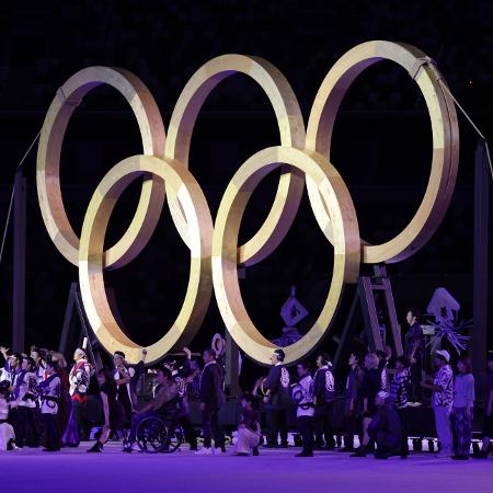 Artistas se apresentam ao lado dos Arcos Olímpicos durante a cerimônia de abertura dos Jogos Olímpicos de Tóquio