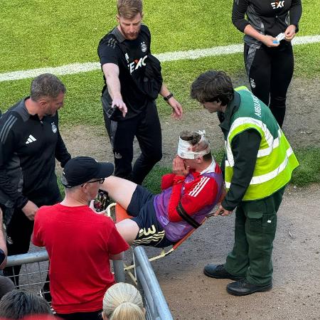 O zagueiro Jack MacKenzie, do Aberdeen, é retirado de campo após ser atingido por uma cadeira - Reprodução/X