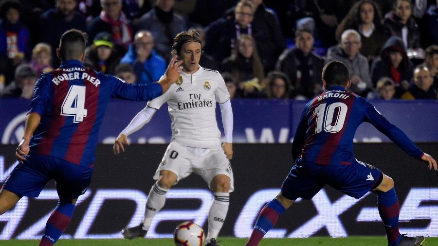 Luka Modric é marcado por jogadores do Levante  -  JOSE JORDAN / AFP
