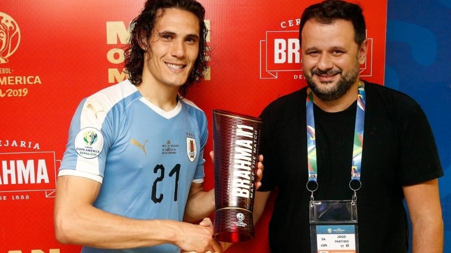 Cavani (e) recebe o prêmio de melhor em campo das mãos de Toninho, dono do Bar do Momo (RJ), após jogo no Maracanã - Staff Images/Conmebol