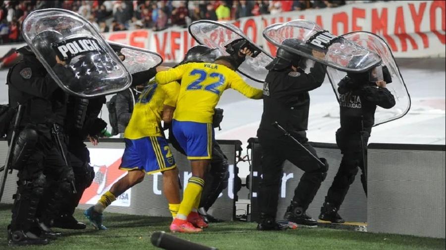 Jogadores do Boca se protegem das garrafadas da torcida do River - Reprodução TV C5N