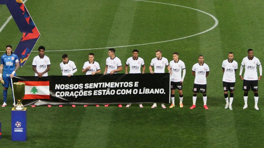 Jogadores do Corinthians entram em campo com faixa de apoio ao Líbano, palco de tragédia na explosão desta semana - PETER LEONE/O FOTOGRÁFICO/ESTADÃO CONTEÚDO