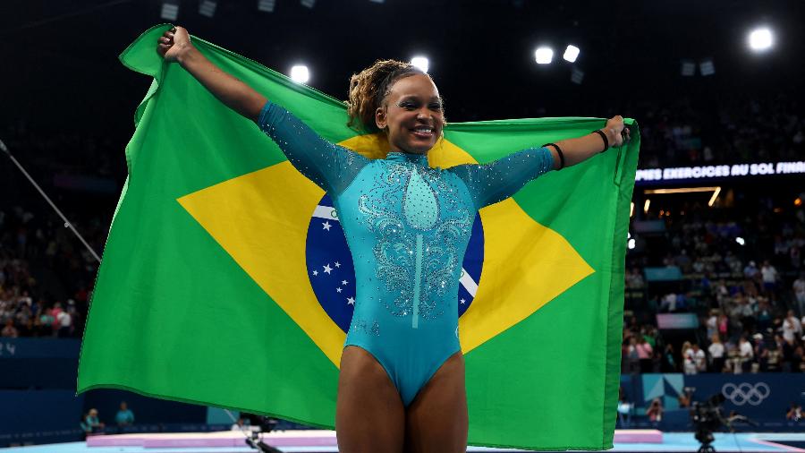 Rebeca de Andrade segura a bandeira do Brasil após conquistar o ouro do solo nas Olimpíadas de Paris-2024