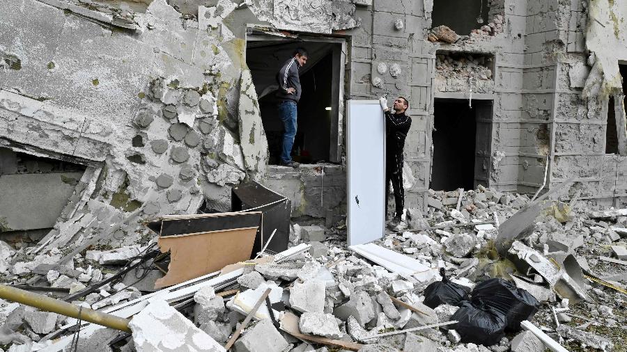 12.set.2022 - Moradores locais ficam do lado de fora de seu prédio parcialmente destruído por um ataque com mísseis em Kharkiv - SERGEY BOBOK / AFP