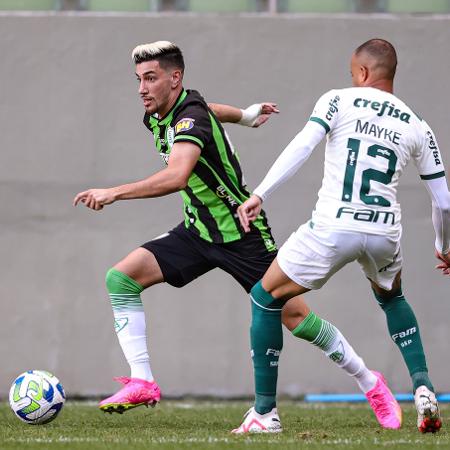 Pedrinho, do América-MG, e Mayke, do Palmeiras, brigam pela bola em partida do Campeonato Brasileiro