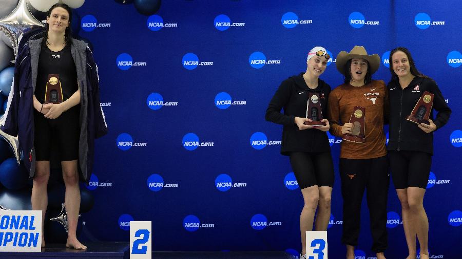 17.3.22 - Lia Thomas, à esquerda, no topo do podio, enquanto Emma Weyant, Erica Sullivan e Brooke Forde posam para foto abraçadas - Justin Casterline/Getty Images