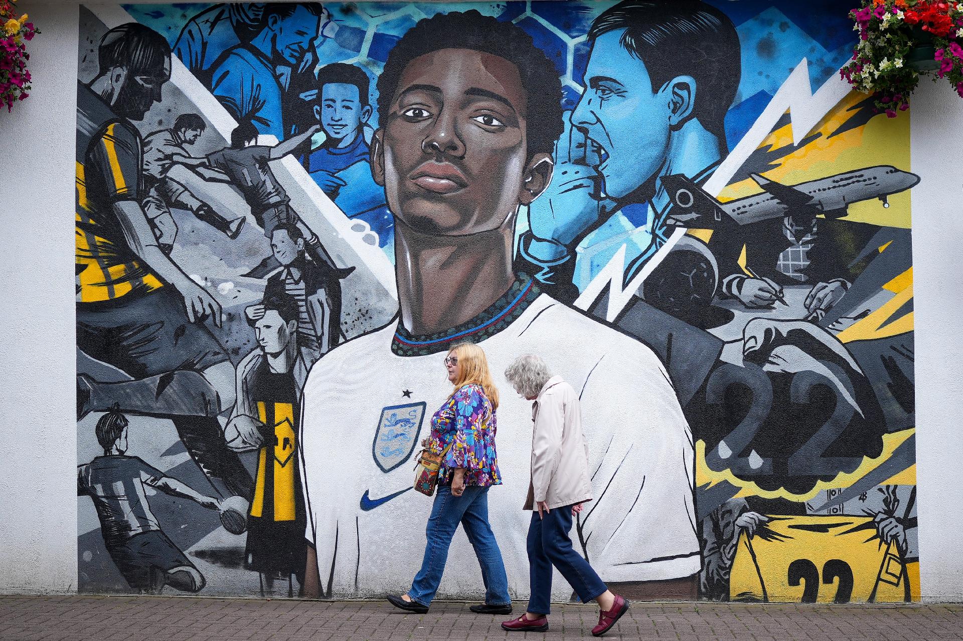 Cidadãos de Stourbridge, na Inglaterra, caminham em frente a um mural com o rosto de Jude Bellingham - undefined