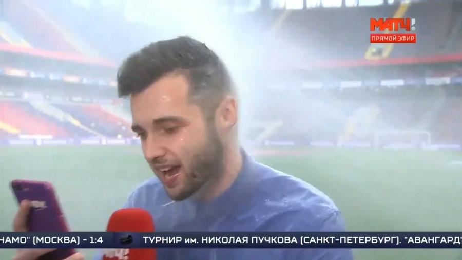 O repórter russo Evgeniy Evnevich toma banhaço do sistema de irrigação da VEB Arena, em Moscou - Reprodução/Twitter
