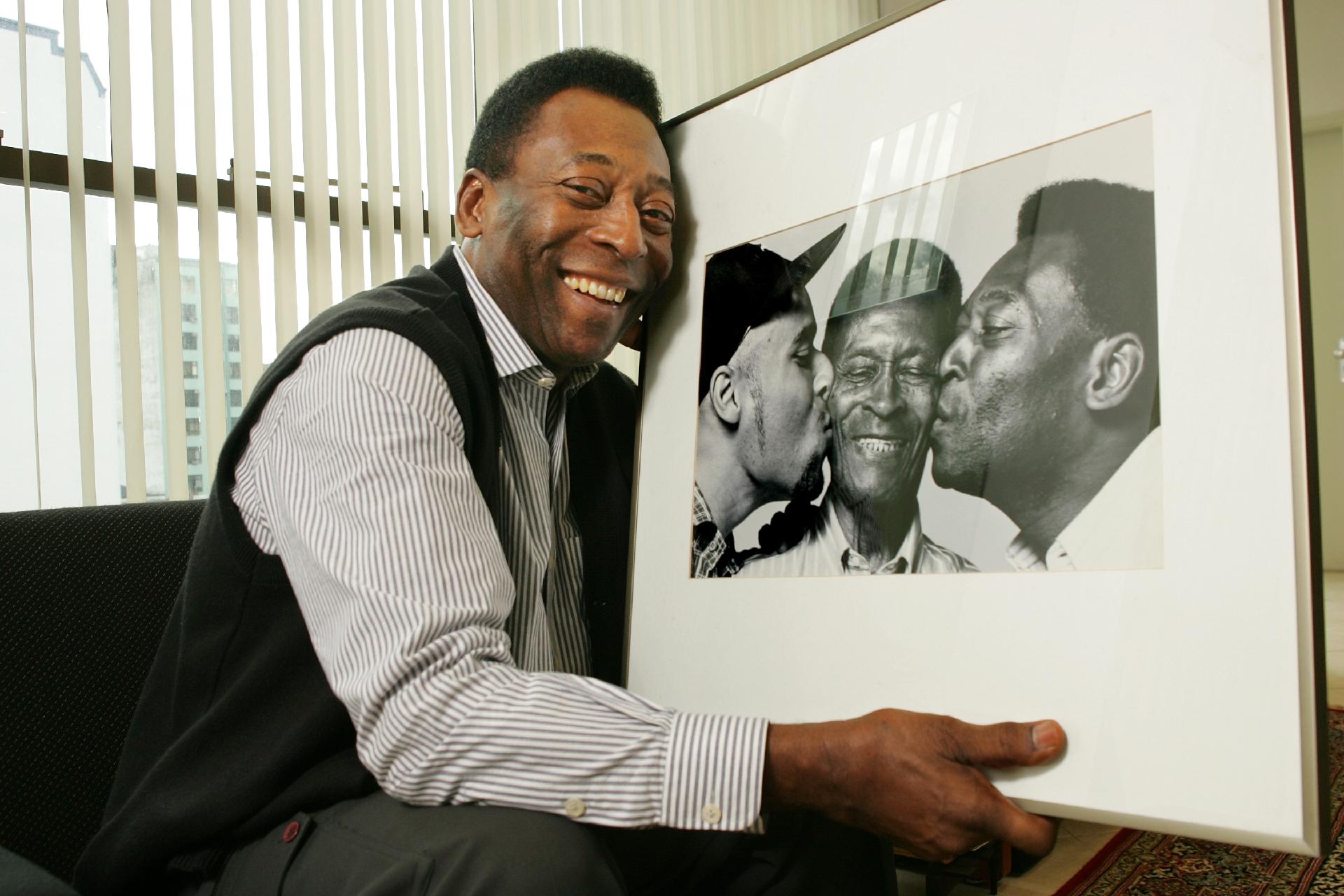 Na imagem, Pelé é fotografado no escritório em Santos, segurando retrato onde aparecem ele, o filho, Edinho, e seu Dondinho, pai do rei. - Eduardo Knapp/Folha Imagem