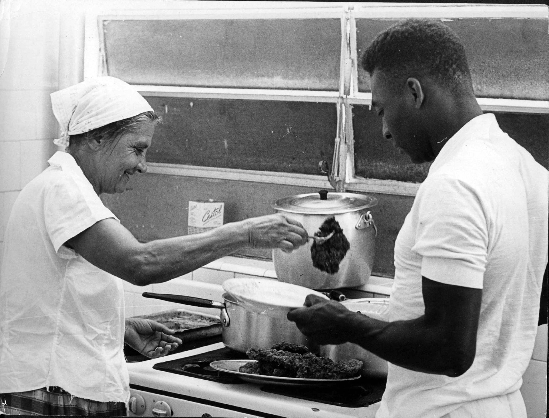 07/12/1964 - A cozinheira do Santos, dona Maria Toledo, serve um bife ao Pelé. O craque sempre procurou alimentar-se bem e descansar bastante. - Estadão Conteúdo