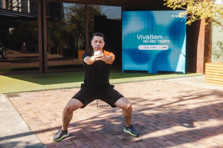 Volte à posição inicial e flexione os joelhos, ficando em posição de meio agachamento.  