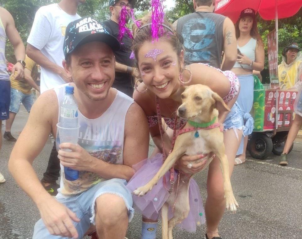 O casal Lucia Giordano, 33, e Renan Paiva, 38, tutores da vira-lata caramelo Pipoca, no bloco Fogo e Paixão - Martha Alves/UOL