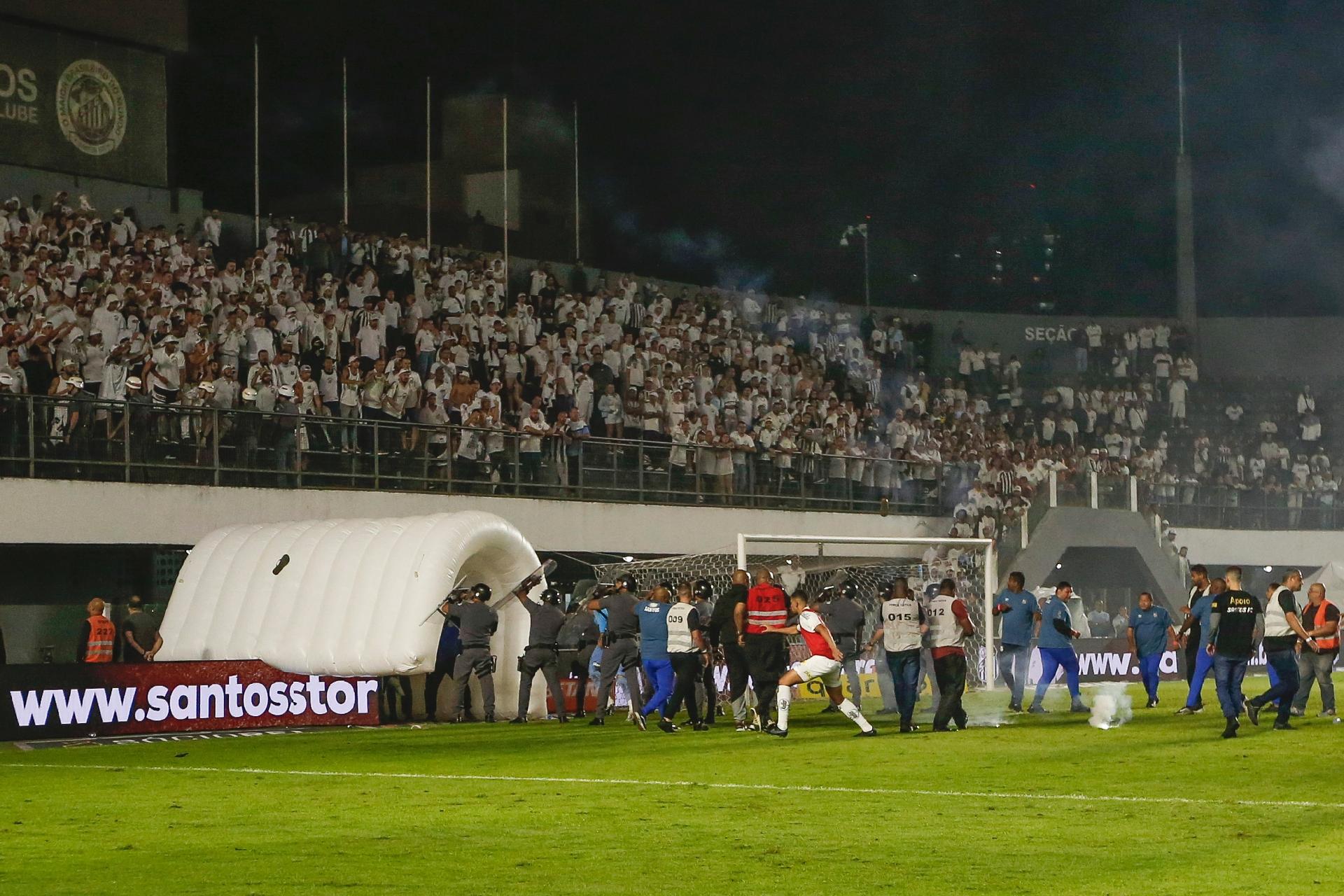 Ricardo Moreira/Getty Images - Jogadores do Santos tentam ir para o vestiário, mas bombas são arremessadas no gramado