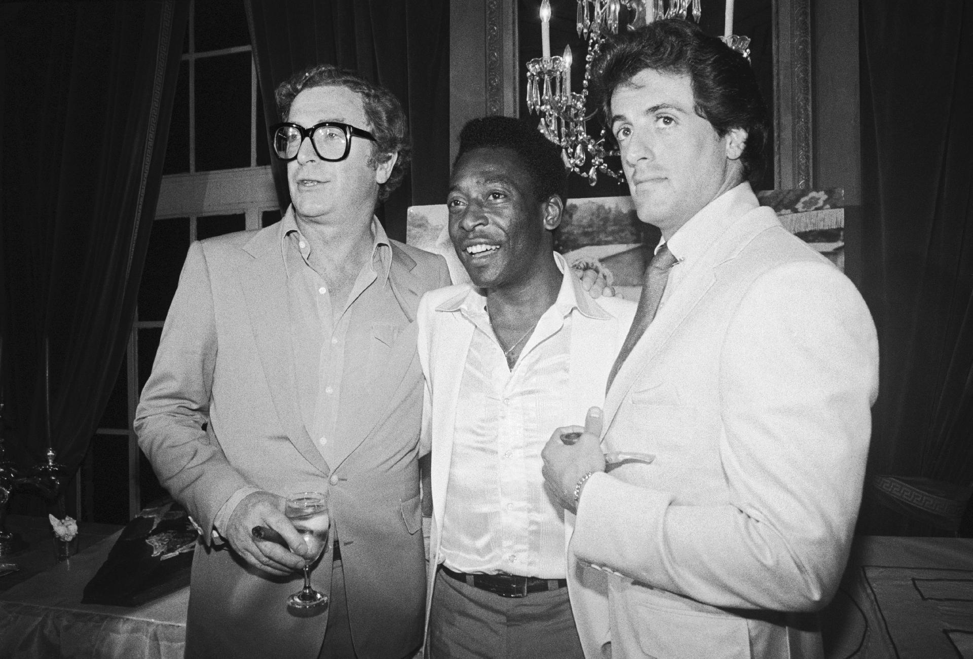 16.jul.1981 - Pelé ao lado dos atores Michael Caine e Sylvester Stallone na festa de estreia do filme "Fuga para a Vitória", que tem os três no elenco. - Reprodução