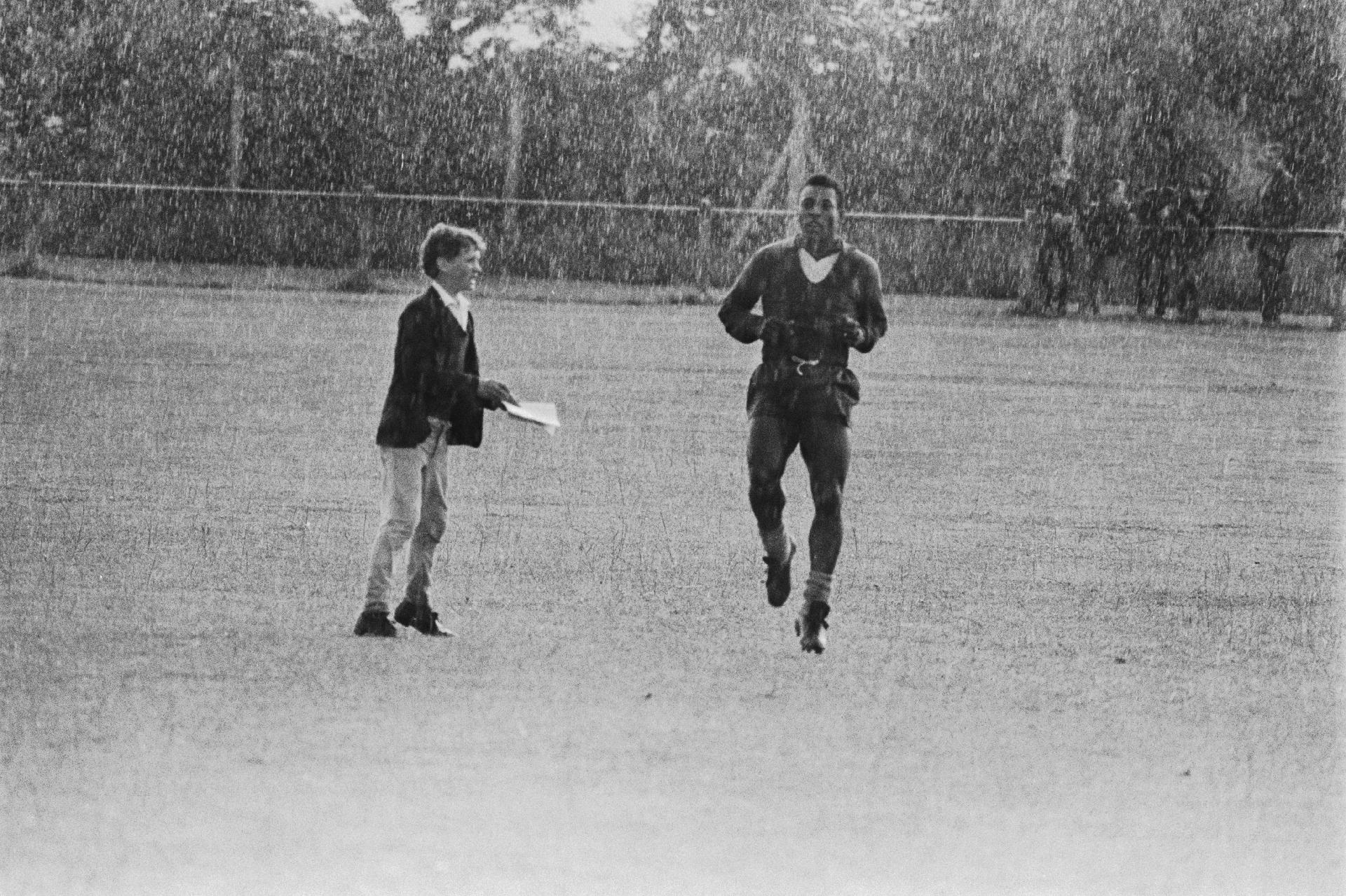 18.jul.1966 - Na foto, um jovem fã de Pelé se aproxima para pedir um autógrafo enquanto o atleta treina debaixo de chuva na cidade de Bolton (Inglaterra), antes de entrar em campo para defender a seleção brasileira em partida contra Portugal. - Getty Images