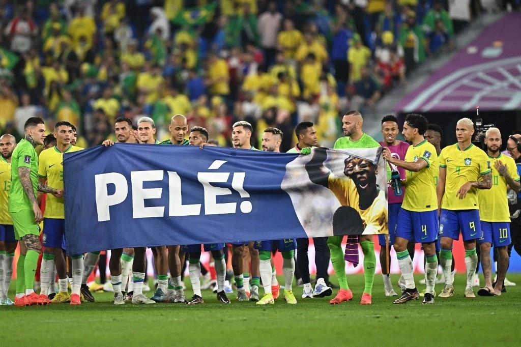 National team athletes hold a banner in honor of Pelé - Manan Vatsyayana/AFP
