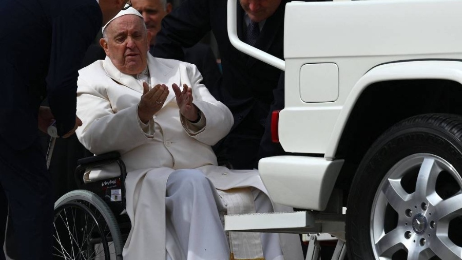 Papa Francisco com seus auxiliares ao ser ajudado a subir no papamóvel hoje - Vincenzo Pinto/AFP
