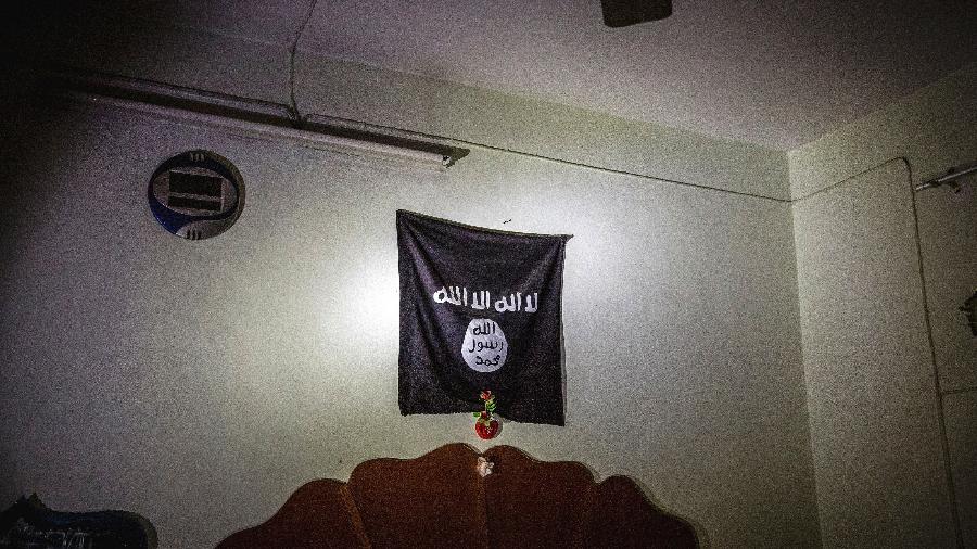 Bandeira do Estado Islâmico sobre cama em uma casa usada por militantes em Mosul