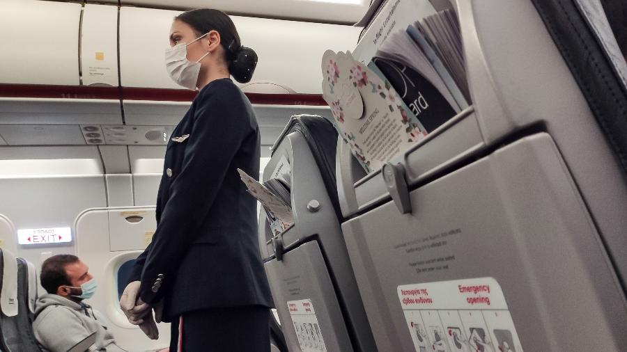 De máscara, comissária de bordo instrui passageiros dentro de avião em meio à pandemia do coronavírus - Nicolas Economou/NurPhoto via Getty Images