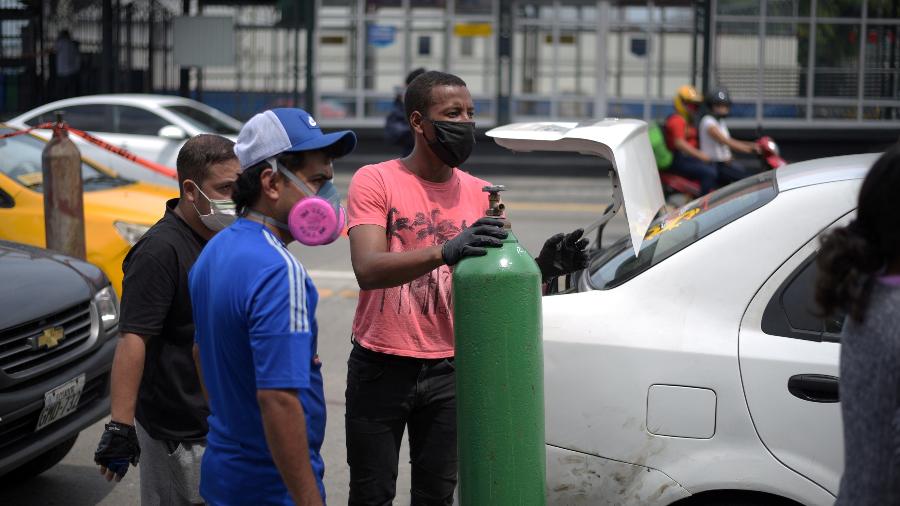 Homem com máscara carrega um cilindro de oxigênio para ser recarregado em Guayaquil, Equador - STRINGER/REUTERS