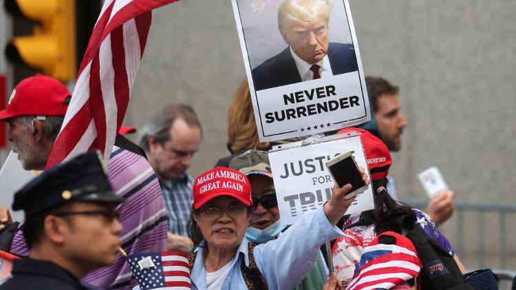 Apoiadores de Donald Trump seguram cartazes de apoio do lado de fora do tribunal
