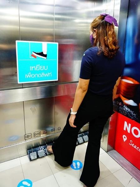 Mulher usa pedal para escolher andar dentro de elevador no shopping Seacon Square, na Tailândia - Divulgação/Seacon Square