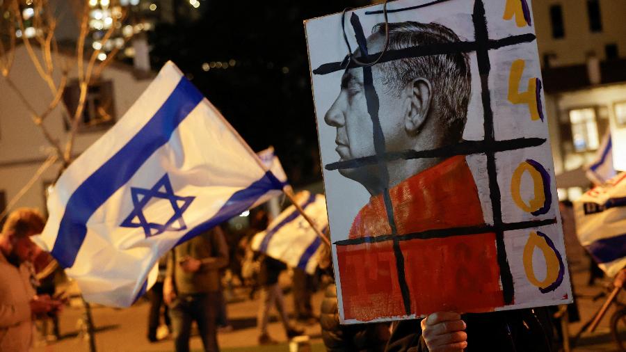Cartazes contra Benjamin Netanyahu são vistos em protesto no centro de Tel Aviv na noite deste sábado (2)