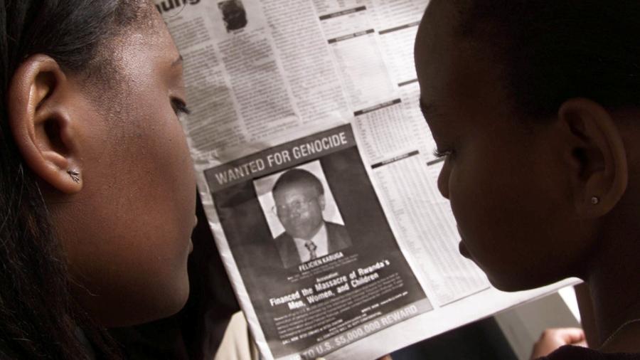 Pessoas veem foto de anúncio em busca do acusado de genocídio Felicien Kabuga - REUTERS/George Mulala