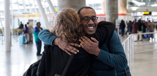 Kamal Fadlalla, que estava impossibilitado de viajar em seu país natal Sudão, abraça a advogada Anita Eliot, no aeporto internacional de Nova York - Alex Wroblewski/The New York Times