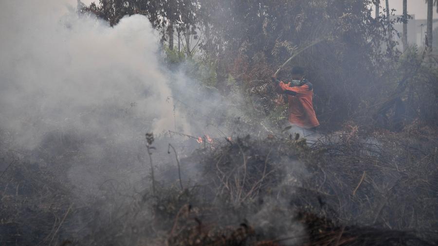 Bombeiro tenta apagar o fogo em Kampar, na província de Riau, Indonésia - Adek Berry/AFP