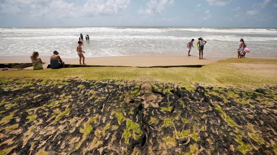 Manchas e banhistas na beira d"água em praia na Bahia; trajetória do óleo pode ter encontrado seu ponto máximo ao chegar em Salvador - REUTERS/Adriano Machado