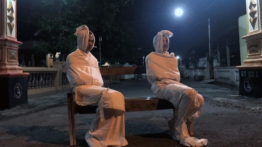Voluntários vestidos como pocong na Indonésia. A figura representa as almas dos mortos que ficaram presas aos corpos e roupas.  - Reuters