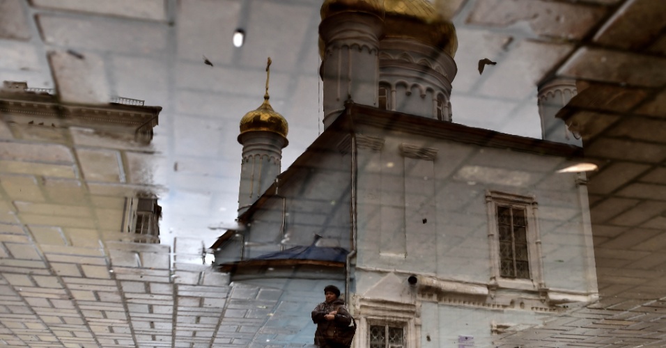 6.nov.2015 - Mulher é refletida em uma poça d'água enquanto passa por igreja no centro de Kazan, na Rússia