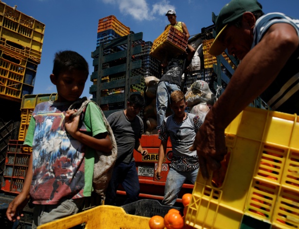 Menino observa cesta de frutas enquanto o caminhão de Humberto Aguilar" é carregado  - Carlos Garcia Rawlins/Reuters