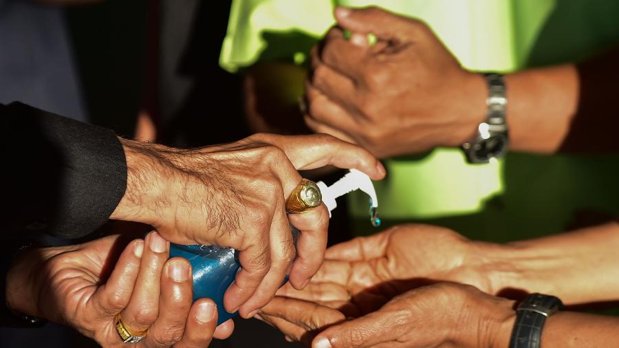 11.mar.2020 - Funcionário de uma estação de ônibus em Narathiwat, na Tailândia, oferece gel para os passageiros limparem as mãos antes de viajarem - Madaree Tohlala/AFP