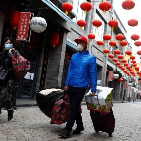 Pessoas usando máscaras de proteção caminham em distrito histórico de Pequim - Reuters