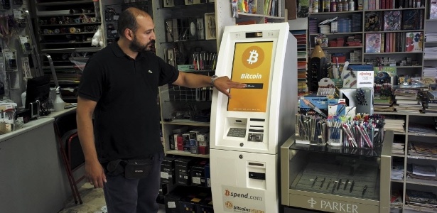 Vendedor explica o funcionamento de um caixa eletrônico de Bitcoins em uma papelaria de Atenas - Dimitris Michalakis/Reuters