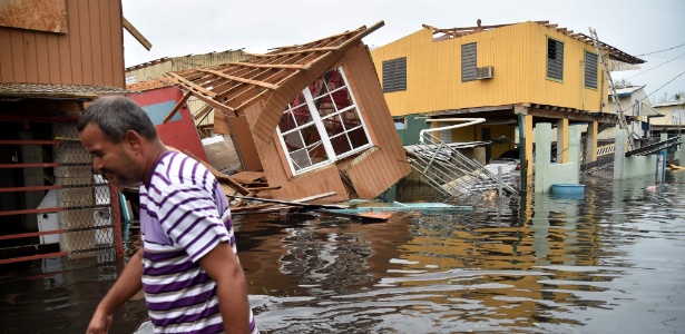 Homem passa em frente a uma casa inundada e destruída pelo furacão Maria em Cataño, em Porto Rico - Hector Retamal/AFP